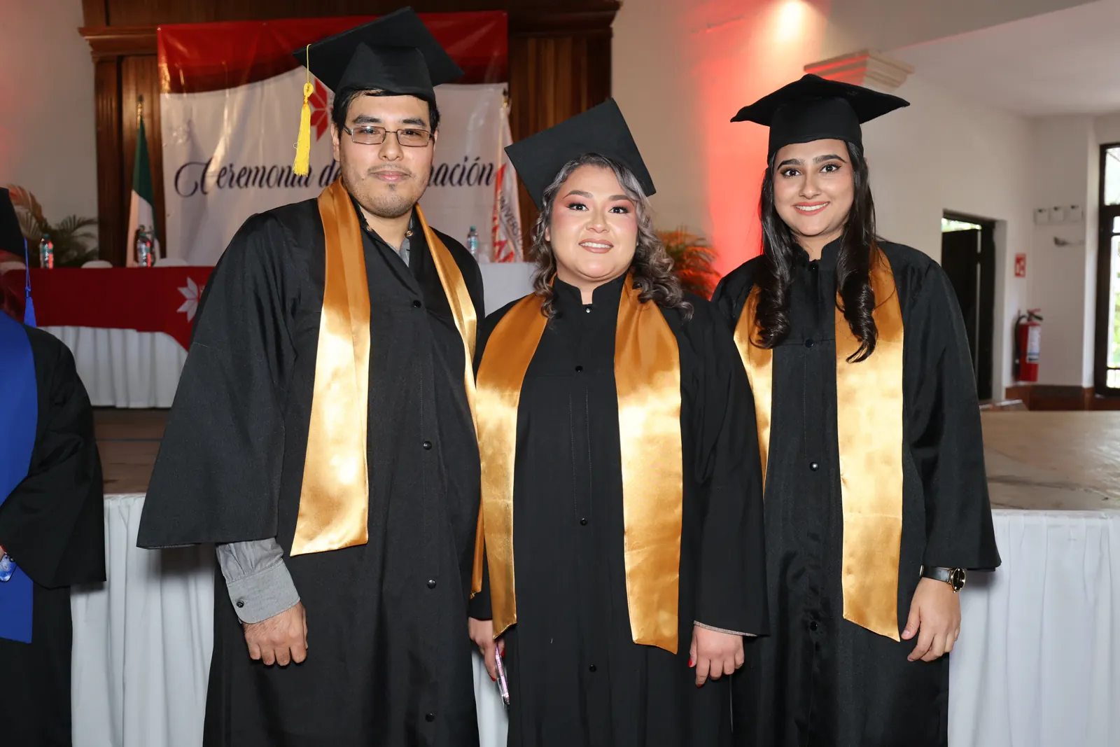Tres egresados de Universidad YAAN con toga y estola dorada